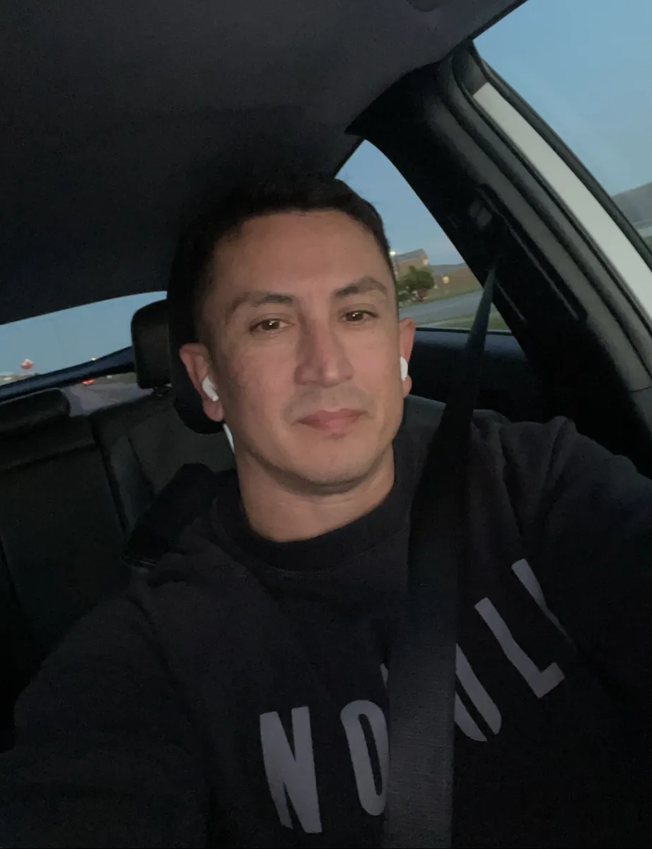 Patrick in a black hoodie taking a selfie in his car